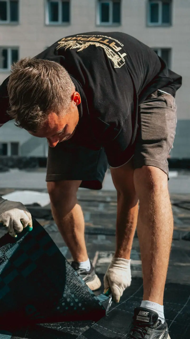 Roofer laying replacement shingles