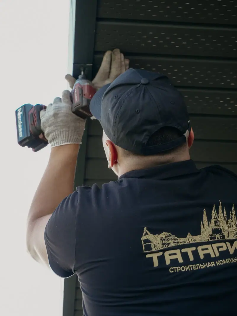 Installer driving fasteners into new siding