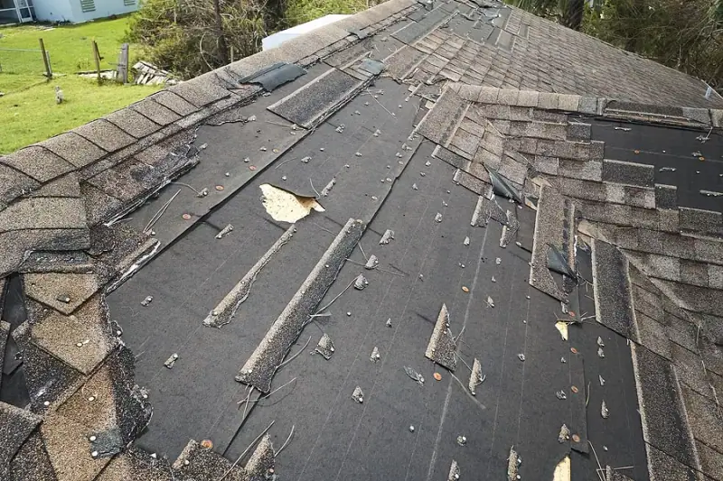 Shingles torn off a roof by wind, leaving the underlayment exposed
