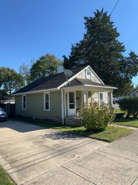 Front exterior of single-story home with cream siding and dark roof in Troy