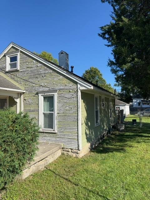Side view of aging wood-sided addition with deteriorated asphalt roof in Troy
