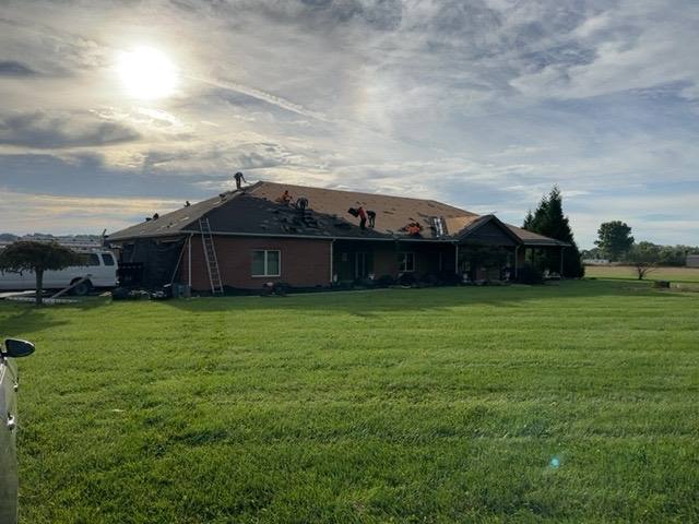 Roof tear-off in progress on a single-story brick home, exposing decking across the full roof plane in Tipp City, OH