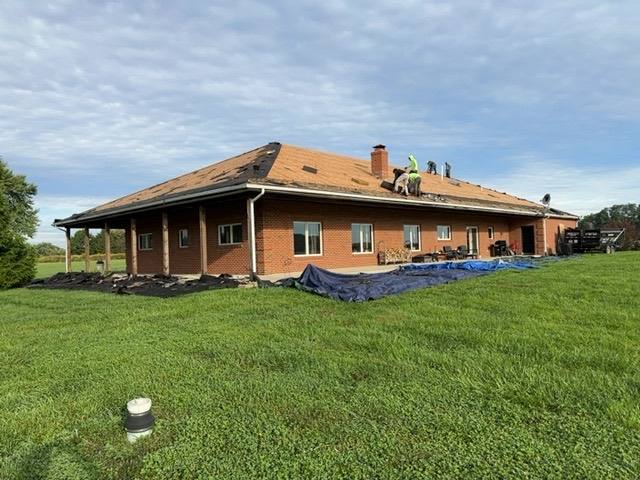 Completed architectural shingle roof on a brick home with extended porch, showing full coverage and final trim work in Tipp City